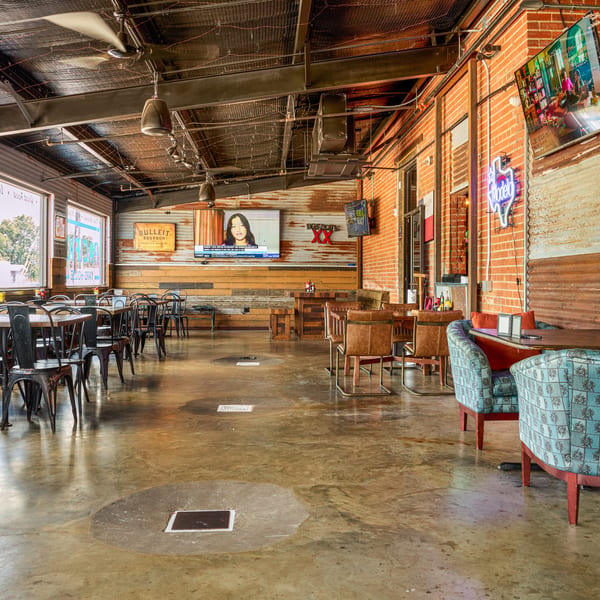 Spacious industrial restaurant interior with exposed brick, corrugated metal, concrete floor, and diverse seating.