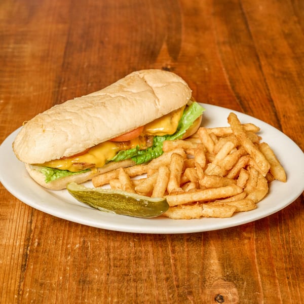 Sub sandwich with melted cheese, lettuce, tomato, golden fries, and a pickle spear.